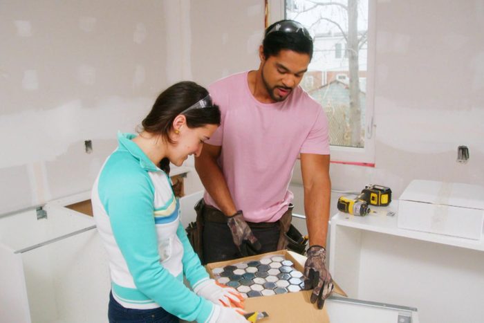 a man and woman opening box of tiles to renovate a home